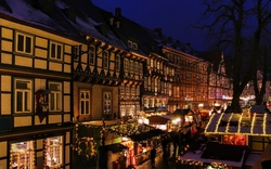 Historische Fachwerkhäuser und Weihnachtsmarkt bei Nacht.