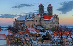 Eine Burg auf einem Hügel mit schneebedeckten Dächern im Winter.