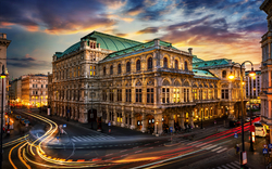 Historisches Gebäude bei Sonnenuntergang mit Verkehr und Lichteffekten in der Stadt.