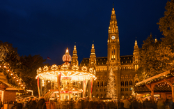 Beleuchtetes Karussell vor einem großen, erleuchteten Gebäude bei Nacht.
