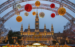 Weihnachtsmarkt mit Lichtern vor einem großen, historischen Gebäude bei Dämmerung.