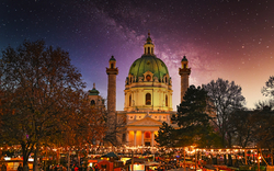 Weihnachtsmarkt vor einer beleuchteten Kuppelkirche bei Nacht