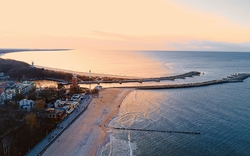 Hafen und Leuchtturm von Kołobrzeg im Winter, Ostsee, mit Strand und Altstadt im Hintergrund.