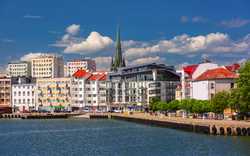 Stadtpanorama mit bunten Gebäuden und Kirchturm am Wasser.