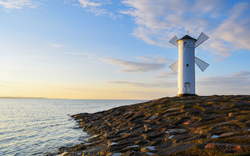 Weißer Leuchtturm am Meer auf Felsen bei Sonnenuntergang
