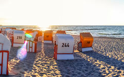 Strandkörbe am Strand bei Sonnenuntergang.