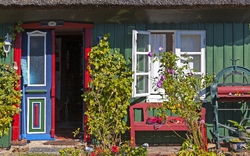 Buntes Fachwerkhaus mit Blumen im Vorgarten bei Sonnenschein.