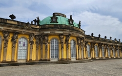 verzierte, gelbe Fassade und grünes Dach des Schloss Sanssouci in Potsdam