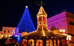 Beleuchteter Weihnachtsmarkt mit Lichterbaum und Pavillon nachts.