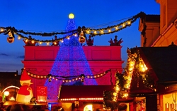 Weihnachtsmarkt mit beleuchtetem Baum und Dekorationen bei Nacht.