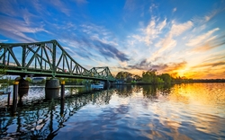 Brücke über einen Fluss bei Sonnenuntergang, Spiegelung im Wasser.