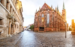 Kirche im gotischen Stil an einer leeren Kopfsteinpflasterstraße bei Sonnenuntergang.