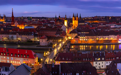 Abendliche Panoramaansicht von Würzburg mit erleuchteten Gebäuden und Fluss.