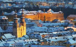 Verschneite Stadtansicht bei Dämmerung mit beleuchteten Kirchen und Gebäuden