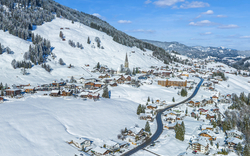 Verschneite Alpenlandschaft mit Dorf und Kirchturm im Winter.