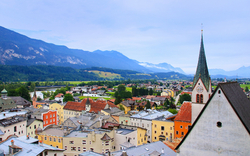 Blick auf eine malerische Alpenstadt mit Kirchengebäude im Vordergrund.