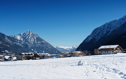 Verschneite Berglandschaft mit Dorf und blauen Himmel.