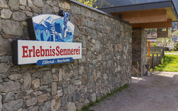 Ein steinernes Gebäude mit einem großen Schild der ErlebnisSennerei Zillertal-Mayrhofen.