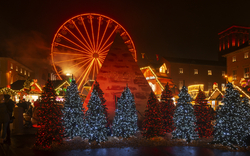 Beleuchteter Weihnachtsmarkt mit Riesenrad bei Nacht.