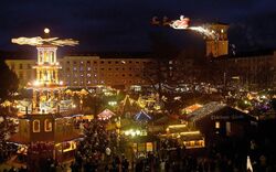 Beschreibung eines beleuchteten Weihnachtsmarkts bei Nacht mit Menschen und Verkaufsständen.