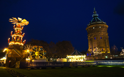 Weihnachtsmarkt in Mannheim mit beleuchtetem Turm bei Nacht