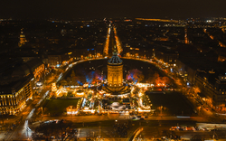 Luftaufnahme einer nächtlich beleuchteten Stadt mit beleuchtetem Turm in der Mitte