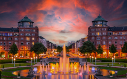 Blick auf den Friedrichsplatz in Mannheim bei Sonnenuntergang mit beleuchtetem Springbrunnen.