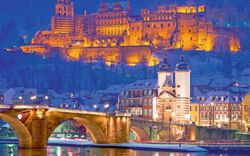 Beleuchtetes Schloss und alte Brücke in Heidelberg bei Nacht mit schneebedeckten Dächern.