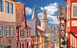 Fachwerkhäuser in einer malerischen Altstadt mit Kirchturm im Hintergrund.