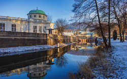 Flusslandschaft im Winter mit historischen Gebäuden und schneebedeckten Ufern.