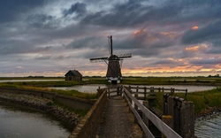 Windmühle an einem kleinen See bei Sonnenuntergang in den Kagerplassen, Südholland, Niederlande.