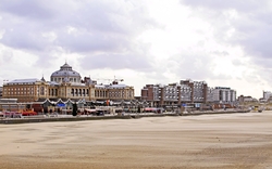 Leere Strandpromenade mit historischen Gebäuden und Wolken am Himmel.