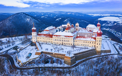 Luftaufnahme eines schneebedeckten Klosters auf einem Hügel im Winter.