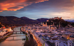 Stadtansicht von Salzburg bei Sonnenuntergang mit Festung Hohensalzburg im Hintergrund.