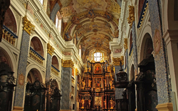 Innenansicht einer prunkvoll verzierten Barockkirche mit Altar und Fresken an der Decke.