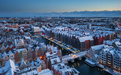 Stadtansicht mit schneebedeckten Gebäuden und Kanälen bei Dämmerung.