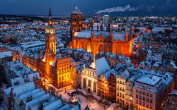 Winterliche Stadtansicht von oben mit beleuchteten Gebäuden im Abenddämmerung.