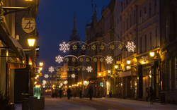 Beleuchtete Stadtstraße im Winter mit Schneeflockendekorationen abends.
