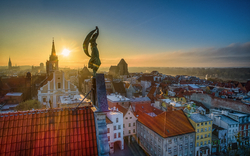 Skyline einer Stadt bei Sonnenaufgang mit Kirchtürmen und Gebäuden im Vordergrund.