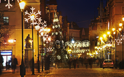 Weihnachtlich beleuchtete Stadtstraße bei Nacht mit geschmücktem Weihnachtsbaum.