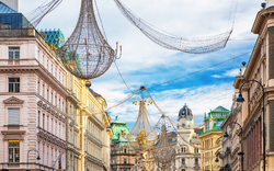 Straßenszene in Wien mit historischen Gebäuden und Weihnachtsbeleuchtung.
