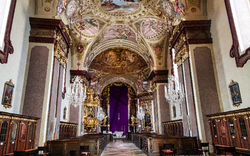 Innenansicht einer prächtig dekorierten Kirche mit Fresken und Kronleuchtern.