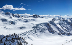 Bergpanorama mit schneebedeckten Gipfeln unter blauem Himmel.