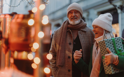 Älteres Paar mit Geschenken auf einem festlichen Markt im Winter.