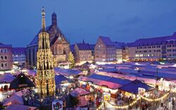 Weihnachtsmarkt mit Ständen und Kirche im Hintergrund in abendlicher Stimmung.