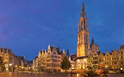 Antwerpen am Abend mit beleuchteten historischen Gebäuden und einem Turm auf einem Platz.