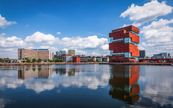 Moderne Gebäude und Wasserreflexionen unter bewölktem Himmel.