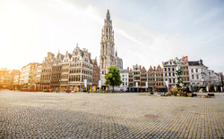 Leerer Marktplatz mit historischen Gebäuden und einer Kirche im Hintergrund.