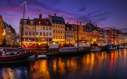 Abendstimmung mit beleuchteten Häusern und Booten an einem Kanal.