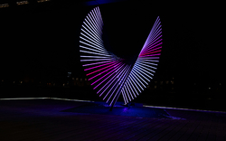 Leuchtende Skulptur mit streifenförmigen LED-Lichtern in der Nacht.